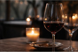 A glass of wine and candles on a table.
